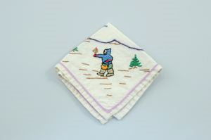 Image of Figure holding plant, one of a set of 2 embroidered napkins, each with single Inuit figure